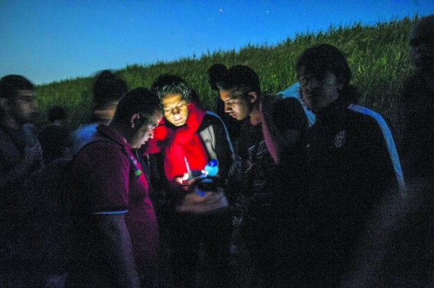 MARTONOS, SERBIA - June 2: Syrian refugees get directions on their phone while traveling through the woods near the Hungarian border on June 2, 2015 in Martono, Serbia. The group walked several miles along the Tisza river at sunset to pass through the border with Hungary at night to avoid the police. Refugees seeking asylum are passing through routes in Eastern Europe in greater numbers as countries like Hungary consider plans to fence off their borders. (Photo by Ann Hermes/The Christian Science Monitor via Getty Images) Refugees48